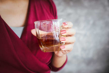 A woman holding a Whiskey Mocktail Sans Drinks
